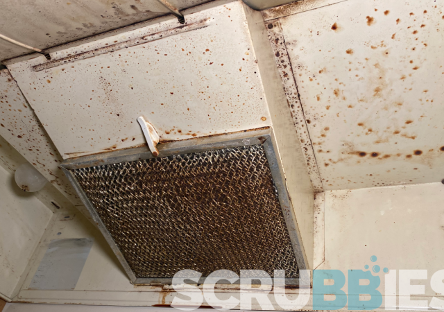 A dirty oven range hood that has grease splatter and buildup that has not been cleaned